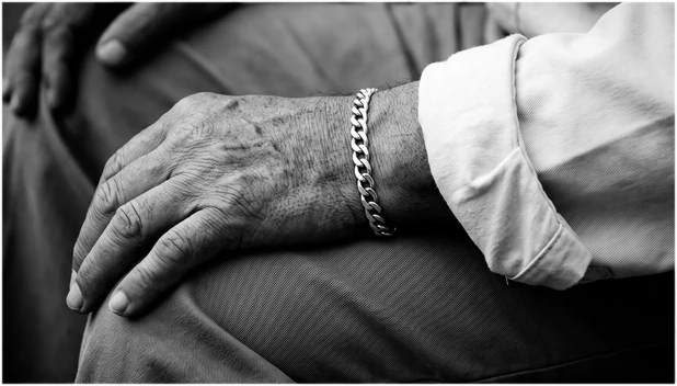 Close crop of hands, a silver chain and a rolled cotton cuff