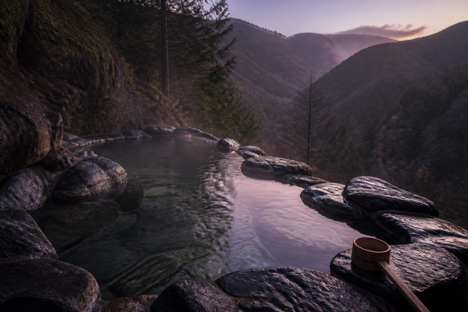 Yumori: the steaming outdoor stone bath looking across the valley in the last light