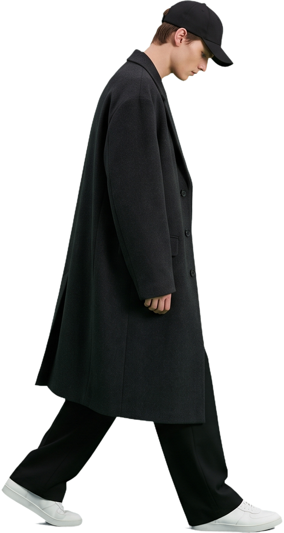 A model walking in an oversized charcoal overcoat, wide trousers and white sneakers