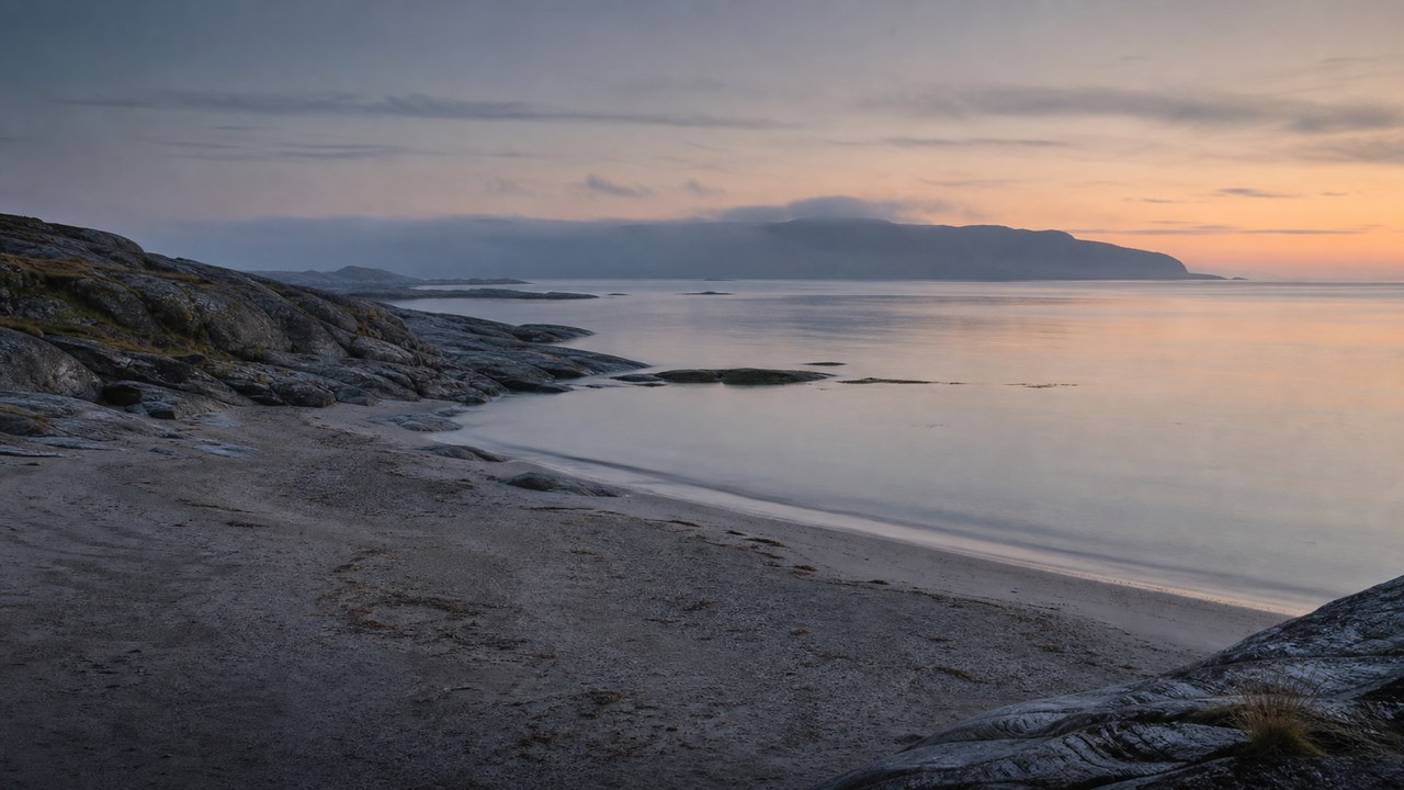 A narrow northern beach of pale stone and flat grey-blue water