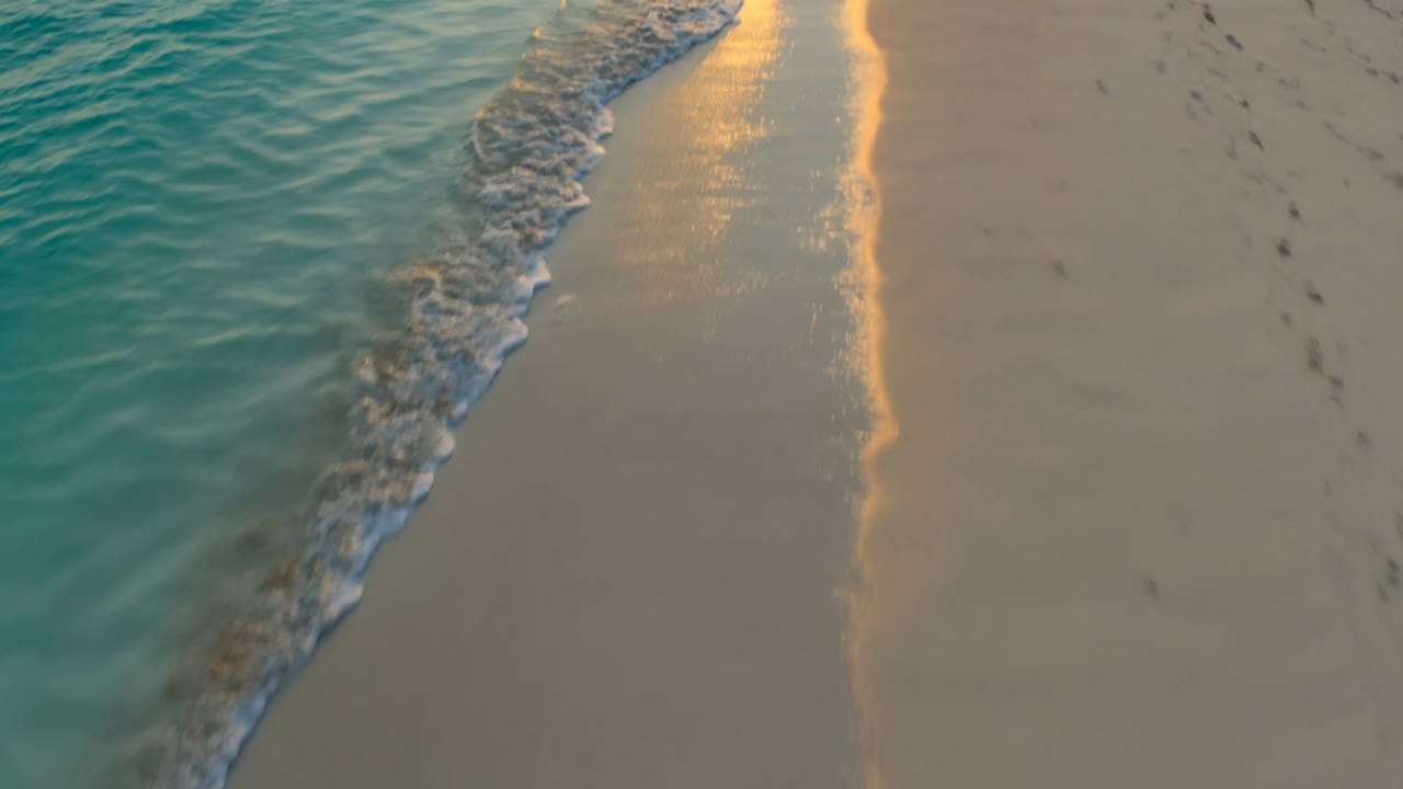 An empty shoreline at golden hour, surf running up pale sand
