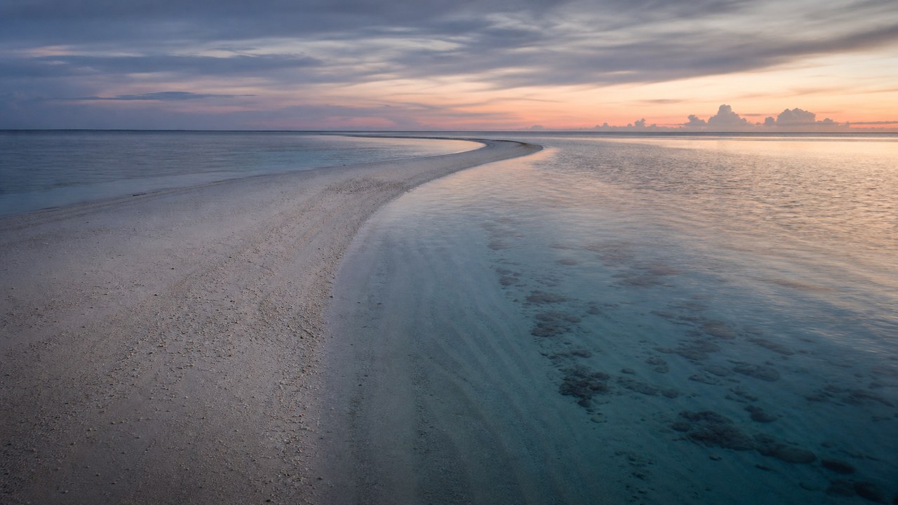 A thin white sandbar running out into turquoise shallows