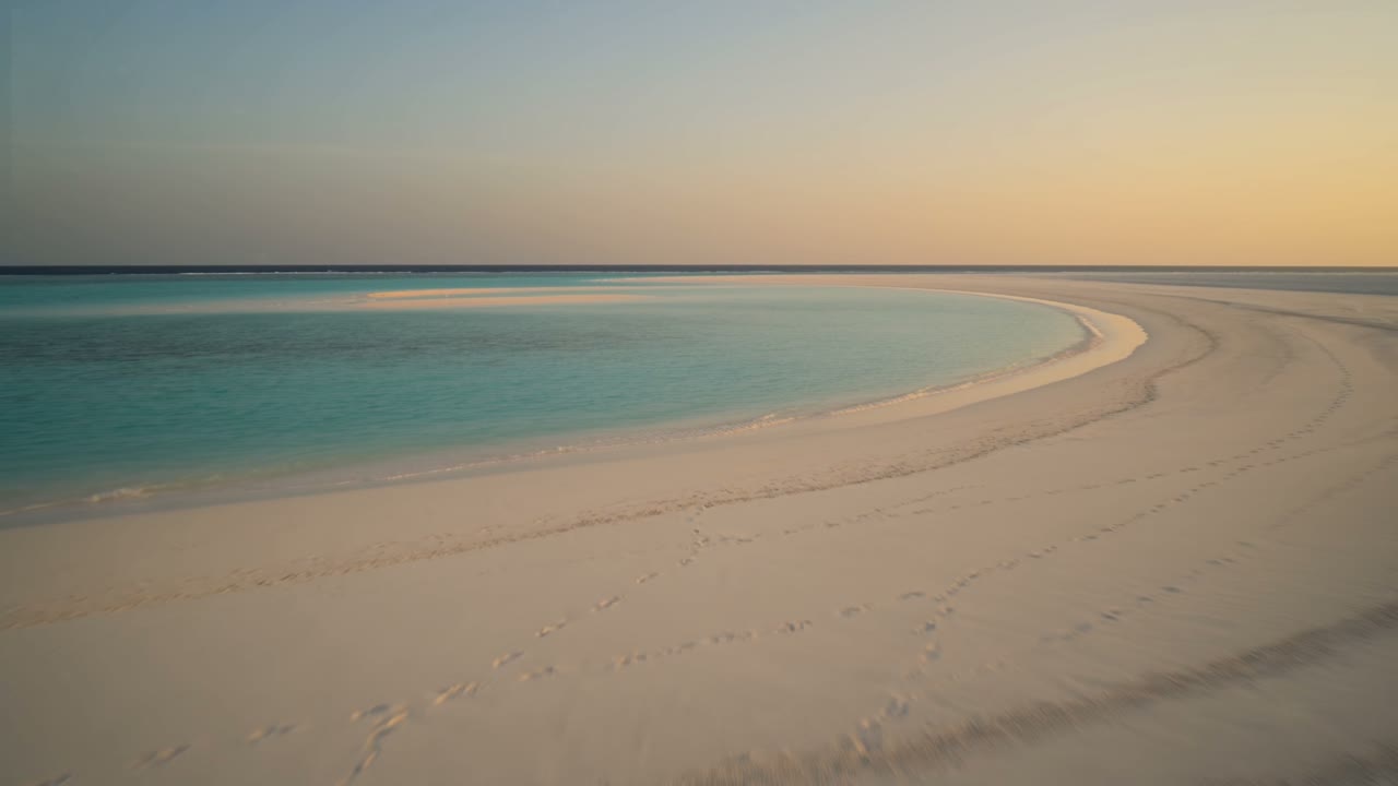 An empty cove at dusk seen from the shade of palms
