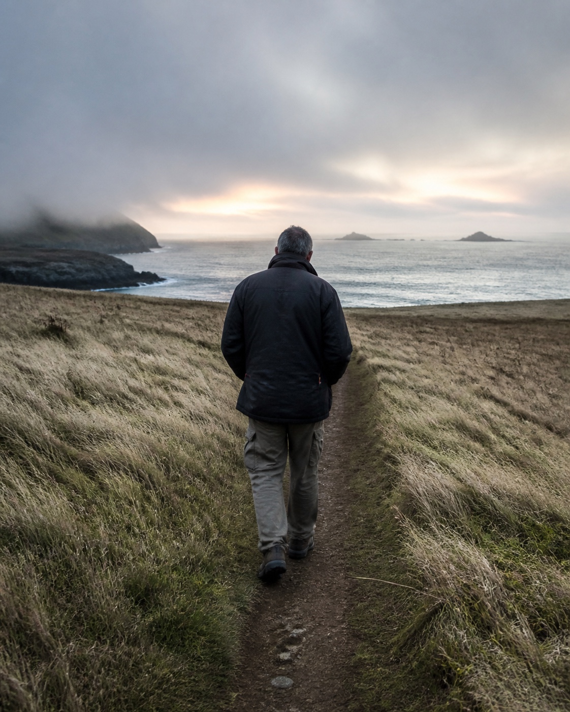 A photographer scouts a coastal path without a camera